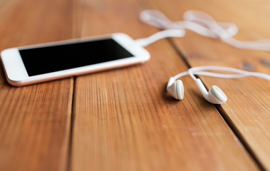 close up of blank smartphone and earphones on wood