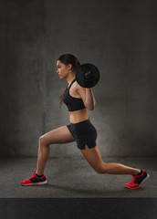 young woman flexing muscles with barbell in gym