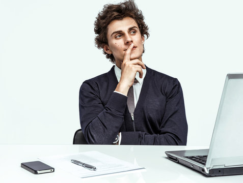 Thoughtful businessman looking up with concentration  at office on grey background. Depression and crisis concept