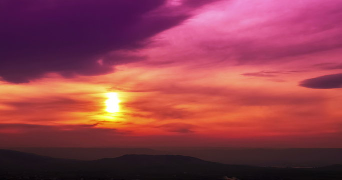 sunset scene with sun fall behind the mountains and clouds in background, time lapse shot, warm colorful sky with soft clouds 4K and HD