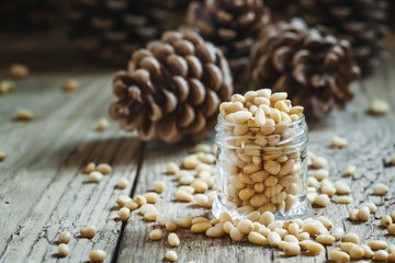Peeled cedar nuts in a jar on the old wooden table against the b