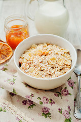 
healthy breakfast of muesli and oatmeal with fruit , milk and dried fruit on wooden background