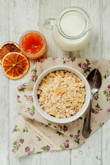 
healthy breakfast of muesli and oatmeal with fruit , milk and dried fruit on wooden background