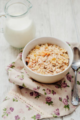 
healthy breakfast of muesli and oatmeal with fruit , milk and dried fruit on wooden background