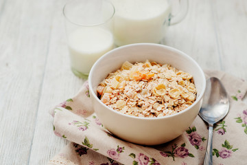 
healthy breakfast of muesli and oatmeal with fruit , milk and dried fruit on wooden background