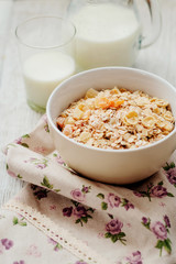 
healthy breakfast of muesli and oatmeal with fruit , milk and dried fruit on wooden background