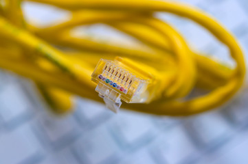 Macro of a yellow network cable in front of a computer keyboard