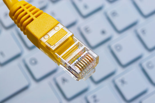 Macro of a yellow network cable in front of a computer keyboard