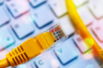 Macro of a yellow network cable in front of a computer keyboard