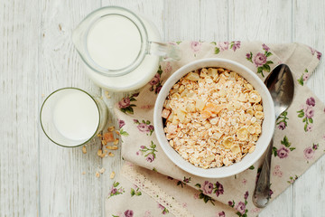
healthy breakfast of muesli and oatmeal with fruit , milk and dried fruit on wooden background