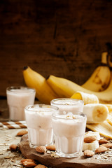 Banana smoothie with milk, oatmeal and almonds on the old wooden
