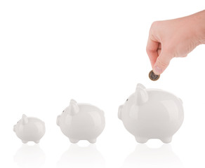 Saving money concept - Growing savings. Hand putting coin into piggy bank