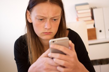 Teenager blickt kritisch auf Smartphone