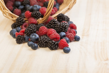 different berries in a basket on a wooden table