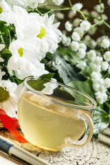 Herbal tea, a bouquet of daisies, old paper, selective focus