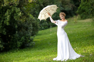 Beautiful bride in park with umbrella