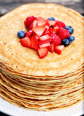 Fresh golden pancakes with strawberries, blueberries and chocolate.