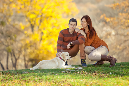 Two lovely people are walking on the nature with labrador