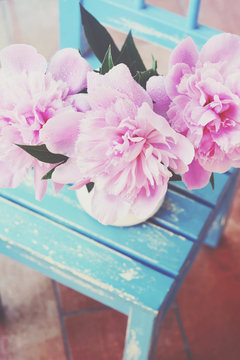 Bunch of peony on shabby blue chair at patio, vintage style