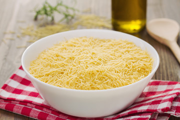 pasta on white bowl on napkin on brown wooden background