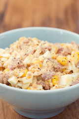 fish salad on blue bowl on brown wooden background