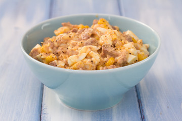 fish salad on blue bowl on blue wooden background