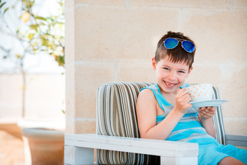 Smiling cute little boy drinking mug coffee tea hot drink