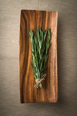 sprigs of rosemary on a wooden plate