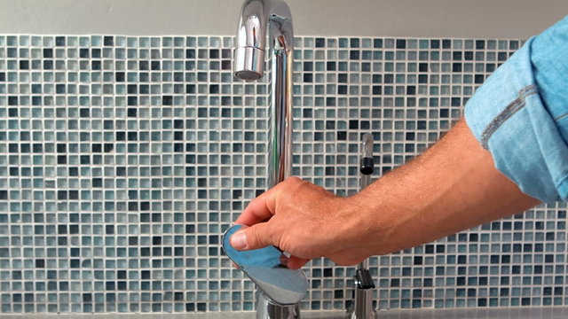 Hand opening a water tap 