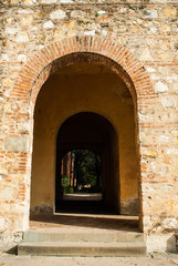 Passaggio ad arco di mattoni, muro di pietre antico