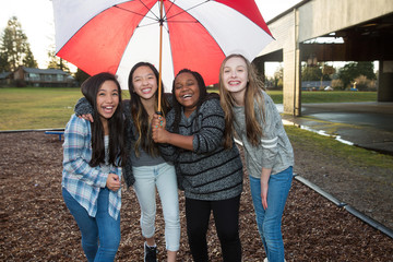 Group of kids under an umbrella in the rain