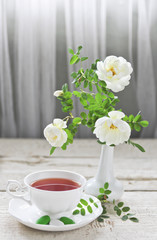 Fototapeta na wymiar cup of tea and roses in a vase