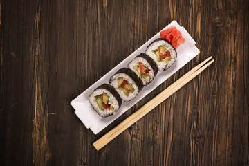 Vegetarian sushi rolls with chopsticks over brown wooden background. Top view. Toned image. Selective focus