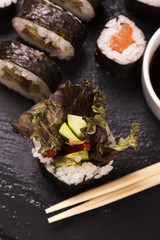 Assortment of sushi rolls with salmon and vegetables, served with soy sauce and chopsticks. Selective foucs