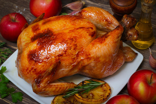 whole chicken noticed roasted with lemon and apples on a plate on a wooden background