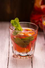 Orange, lemon, lime cocktail drink with mint in a glass over grunge wooden background. Selective focus