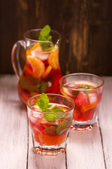 Sangria with fruits and mint leaves in glasses over wooden background. Selective focus