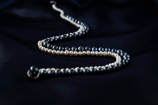 a necklace of black and white pearls on a dark blue background