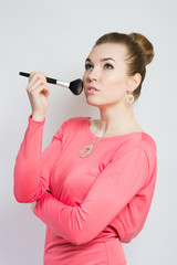 beautiful girl with makeup brushes for makeup in a pink dress