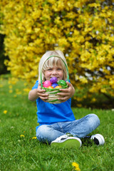 Smiling  little boy holding  basket full of colorful easter eggs