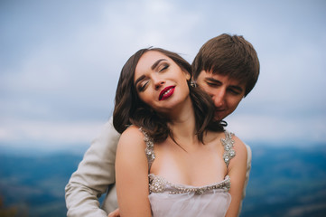 happy newly married couple posing in the mountains