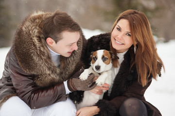 Naklejka na ściany i meble Happy couple and their dog Jack Russell Terrier at the winter park