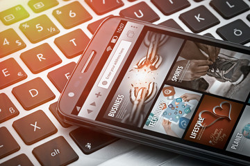 news on smartphone screen on laptop at office macro