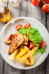 Grilled chicken breasts served with fries and fresh salad