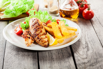 Grilled chicken breasts served with fries and fresh salad