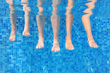 Funny underwater family legs in swimming pool, under water view of mother and kids, vacation and...
