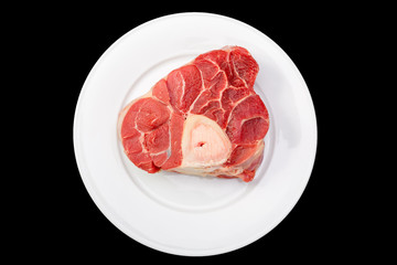 one piece of raw beef meat with the bone in the middle on black background