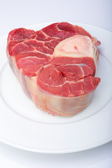 one piece of raw beef meat with the bone in the middle on a white background