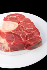 one piece of raw beef meat with the bone in the middle on black background