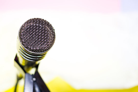 Silver microphone on rack close-up left. Bright blurred background. Space for text.
